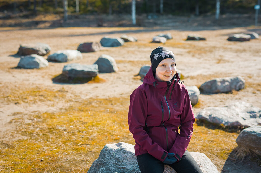 Laura Loven istuu suurella kivellä ja hymyilee.