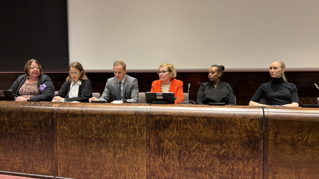 Kansanedustajat istuvat auditorion edessä pöydän takana keskustelemassa.