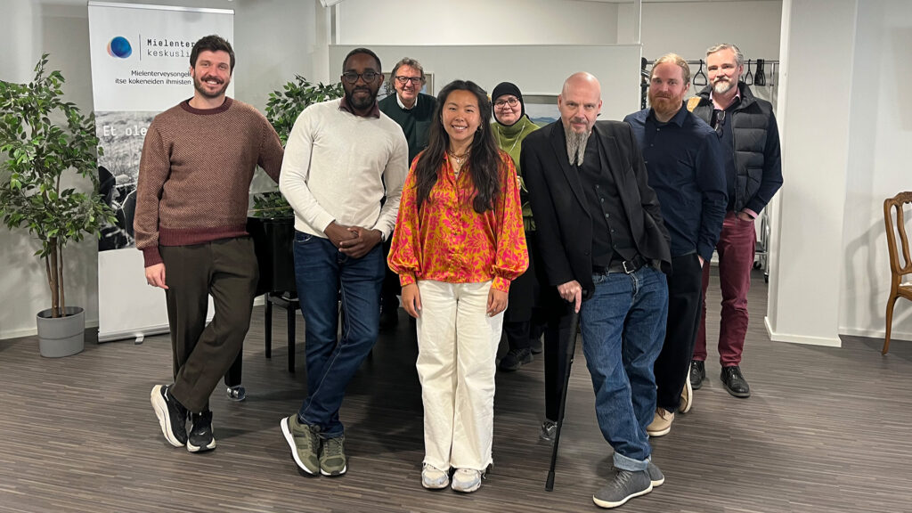 Gamian-Europen tiimin neljä jäsentä seisovat rivissä Mielenterveyden keskusliiton puheenjohtaja Eveliina Lafghanin, toiminnanjohtaja Olavi Sydänmaanlakan, juristi Oskari Korhosen ja Sosped-säätiön toiminnanjohtaja Lassi Rajamäen kanssa. Kaikki hymyilevät.