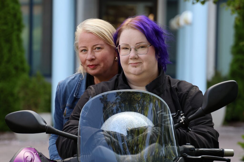 Pääkaistan työntekijät Tuija Nissinen ja Kaika Toivanen istuvat moottoripyörän kyydissä.